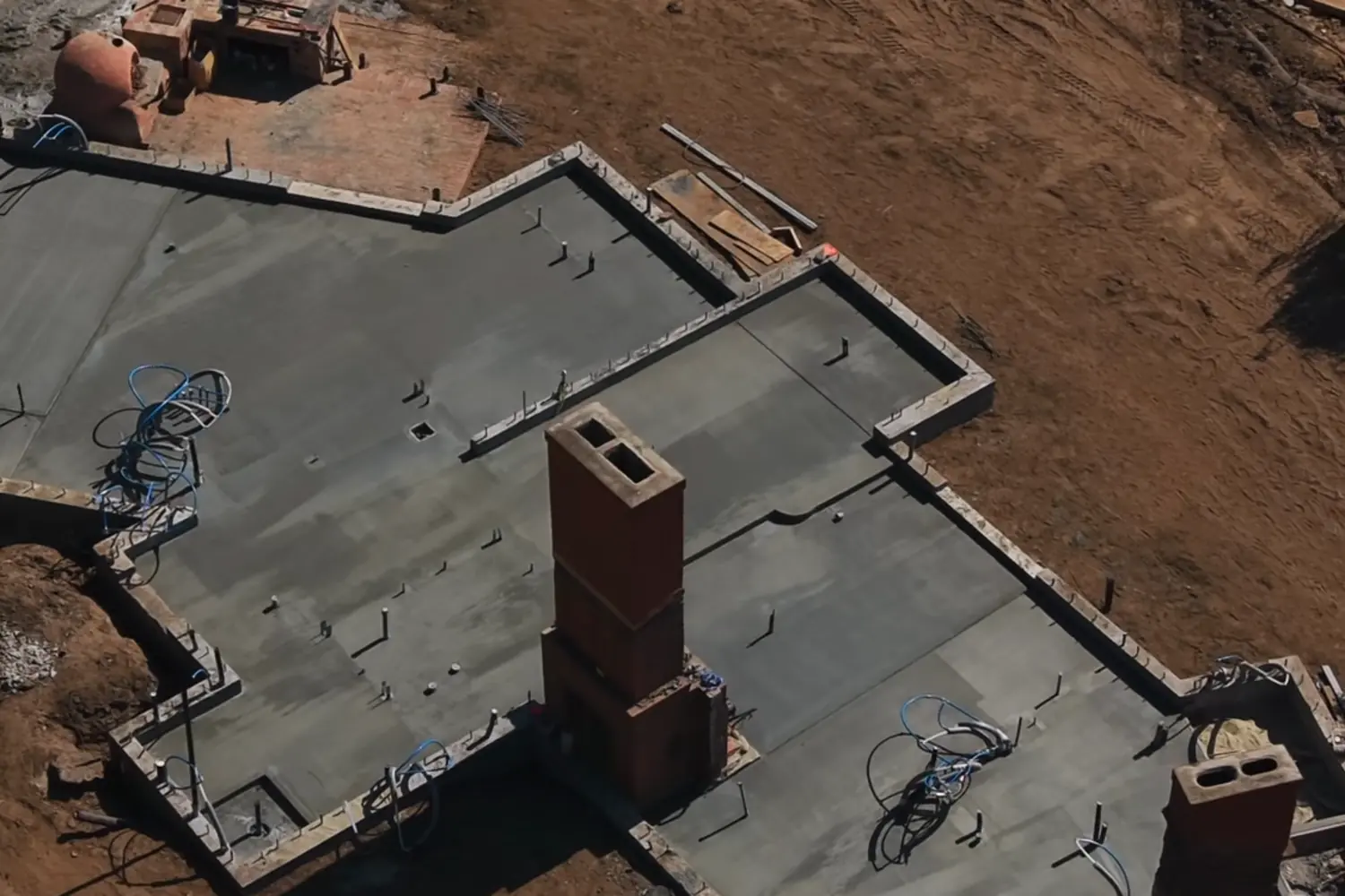 A poured concrete foundation with a brick chimney base, seen from above